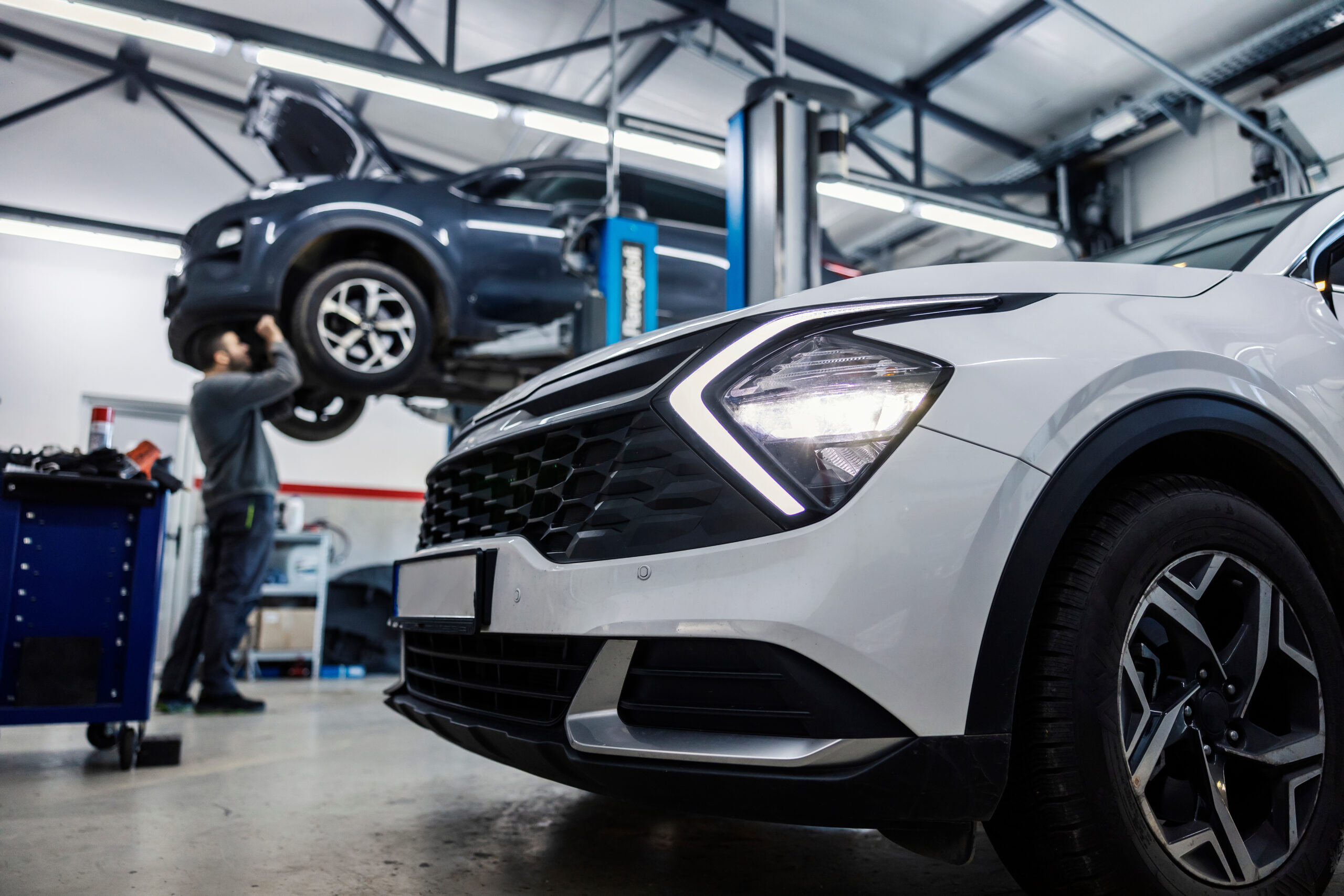 Selective focus on a car in foreground with auto mechanic repair